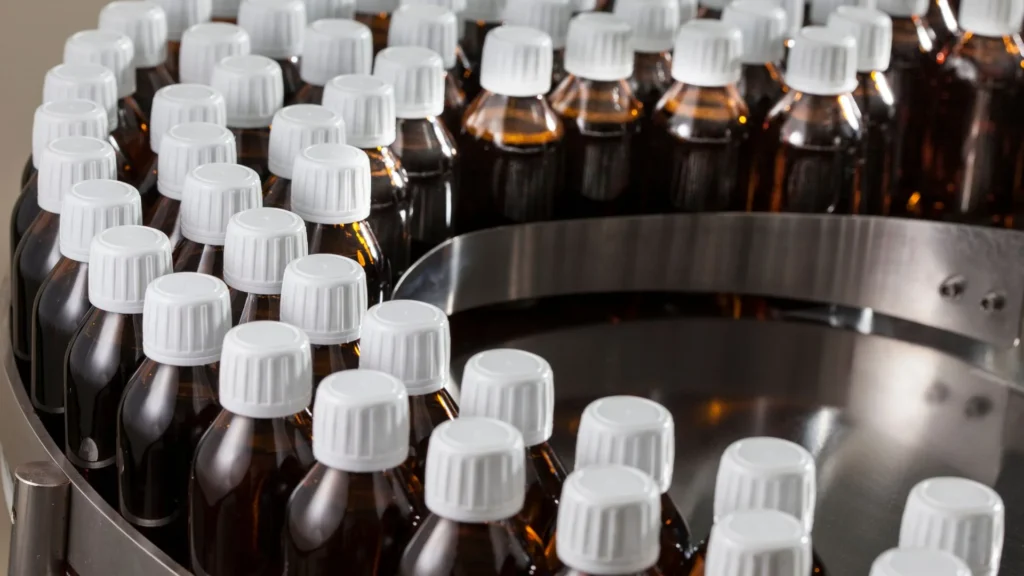 a group of brown bottles with white caps in a machine